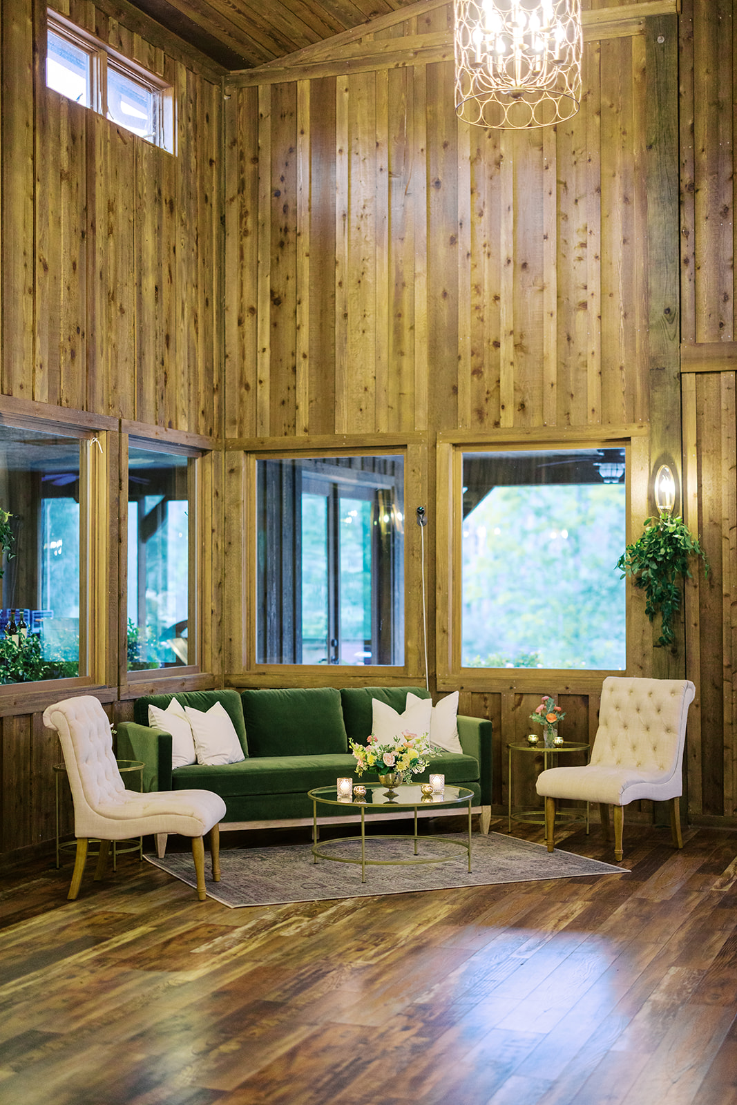 An inviting lounge area inside the event center at Luna's Trail Farm, showcasing plush green and cream seating with soft lighting, rustic wood-paneled walls, and stylish decor.