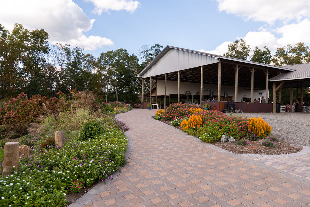 A vibrant view of Donnaha Valley Farm showcasing colorful flower beds lining a paved path leading to the spacious pavilion.